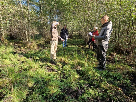 Fem personer i grönskande naturmiljö en solig dag.